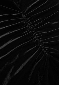 Čierny sametový textil s nadýchanou textúrou, vertikálnym zberaním, hladkým povrchom a jemným leskom. Ideálny na elegantné odevy.