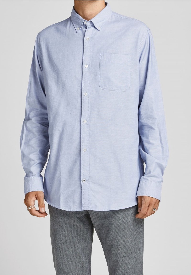 Ljusblå långärmad skjorta med knäppbar krage, en bröstficka och subtil struktur. Försedd med vita knappar fram.