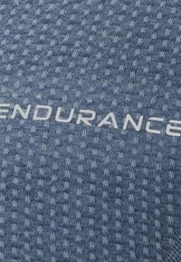 Struktureret blå stof med et rutemønster. Ordet "ENDURANCE" vises i hvid, der skarpt kontrasterer mod baggrunden.