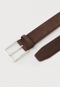 Καφέ σουέντ ζώνη με ασημένια μεταλλική αγκράφα· διαθέτει ομαλή υφή, ευθεία μορφή και τακτοποιημένη ραφή κατά μήκος των άκρων.