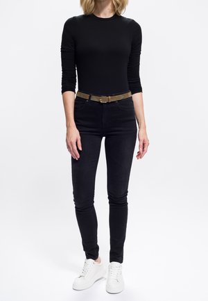 Musta pitkähiha-yläosa yhdistettynä tummiin pillifarkkuihin ja valkoisiin tennareihin. Ruskea vyö, jossa metallinen solki, tuo kontrastia asuun.