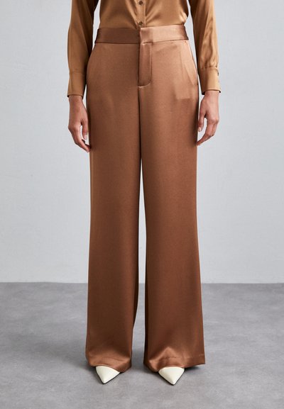Wide-leg trousers in a smooth, shiny brown fabric. Features a flat waistband, side pockets, and pointed white heels.