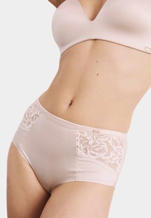 Kvinde iført lyserødt højttaljet undertøj med blonder og en matchende bh mod en neutral baggrund.
