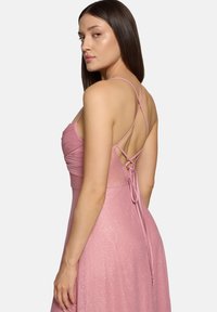 Rosa, glitzerndes Kleid mit dünnen Trägern und einem gekreuzten Design auf der Rückseite. Tailliertes Oberteil, das in einen ausgestellt Rock übergeht. Glatte Textur.