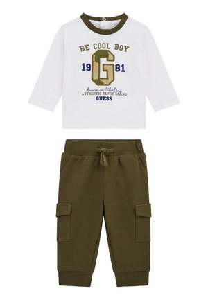 Bijela košulja dugih rukava s zelenim i mornarskim uzorkom, uparena s maslinasto zelenim krojenim hlačama koje imaju bočne džepove i elastičnu traku oko struka.