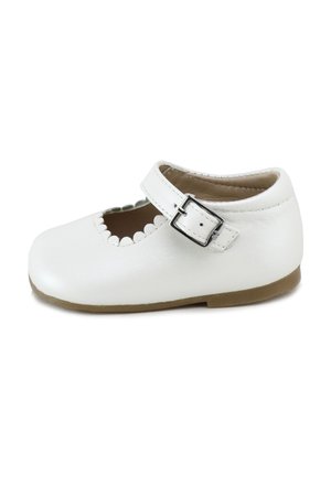 Zapato de bebé de cuero blanco con borde ondulado, correa ajustable con hebilla y suela marrón claro, visto de lado sobre un fondo blanco.