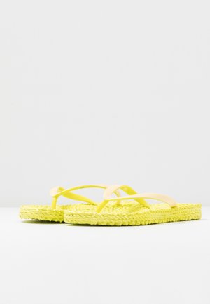 Pair of yellow flip-flops with textured sole and thin straps on a plain white surface against a light gray background.