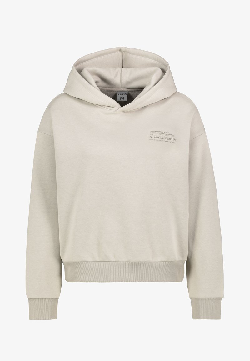 Lichtgrijze, cropped hoodie van zacht materiaal. Heeft een grote capuchon, lange mouwen en bedrukt tekst aan de voorkant links. Ribbelboorden en -zoom.