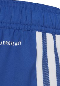 Blauwe sportshorts met een gestructureerde stof, elastische tailleband en witte strepen aan de zijkanten met "AEROREADY" in het wit gedrukt.