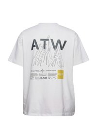 Hvid bomulds t-shirt med et bjergmotiv, "ATW" tekst og flere tryk i grå og gul på bagsiden. Korte ærmer og afslappet pasform.