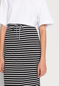 Černobílá pruhovaná sukně s elastickým pasem a šnůrkou. Vyrobena z měkké látky, délka po kolena s volným střihem.