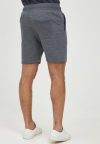 Grå shorts med en struktureret finish, elastisk talje og en baglomme, parret med hvide sneakers.