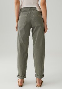 Olijfgroene broek met een relaxte pasvorm, voorzien van opgerolde mouwen, twee achterzakken en een label op de tailleband. Gemaakt van zacht stof.