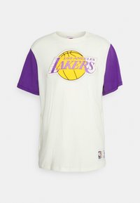 Camiseta de los Los Angeles Lakers en color crema con mangas cortas moradas. Presenta un gráfico de baloncesto amarillo y texto bordado en el frente.