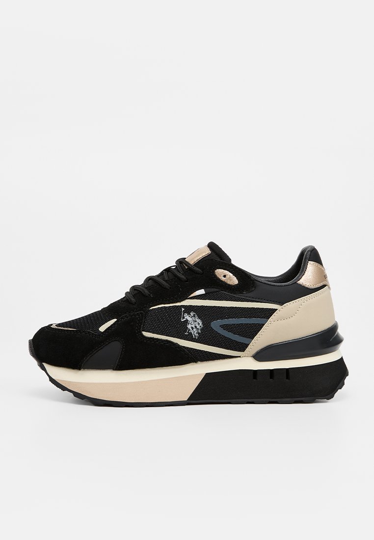 Zapatilla negra y beige, con materiales de ante y malla, con una suela gruesa y un acento de logo, diseñada con líneas curvas y un cierre de cordones.