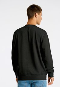 Sudadera negra de manga larga, con cuello redondo y puños acanalados. Presenta una textura suave y un diseño de corte recto.