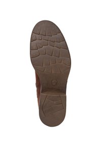 Brun lädersula med en strukturerad gummiyta. Har ett mönster för grepp och en logotypprägling nära hälen. Rundad form.