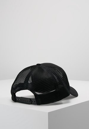 Czarna siatkowa czapka baseballowa z regulowanym paskiem typu snapback, spoczywająca na białej, kątowej powierzchni na tle jednolitego szarego tła.