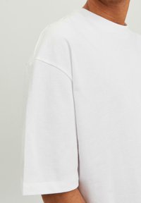 Hvid bomulds t-shirt med ribbet rund halsudskæring og korte ærmer, kendetegnet ved en afslappet pasform og blød struktur.