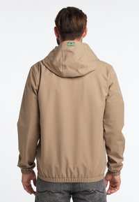Světle hnědá kapucí opatřená bunda s elastickými manžetami a lemem, vyrobená z hladkého, texturovaného materiálu. Na krku má značkovou cedulku.