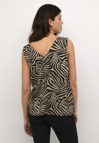 Haut sans manches noir et beige avec un décolleté en V et un motif zèbre. Tissu doux avec un design fluide, mettant en valeur un dos courbé.