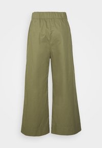 Szerokie oliwkowozielone spodnie z elastycznym paskiem w talii, o skróconej długości, bez widocznych kieszeni, zaprezentowane na tle czystej bieli.