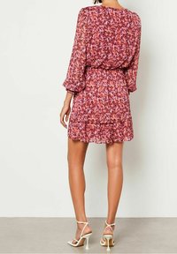 Lyhythihainen, polvipituinen mekko, jossa on kukkakuosi vaaleanpunaisen ja violetin sävyissä. Kevyt, läpikuultava kangas, jossa on röyhelöhelma ja elastinen vyötärö.