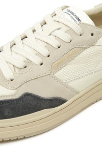 Tenisice koje se sastoje od kombinacije bež kože, sive antilop kože i teksturirane mrežice. Okrugli vrh, podstavljeni okovratnik i tonirane vezice s oznakom s strane.