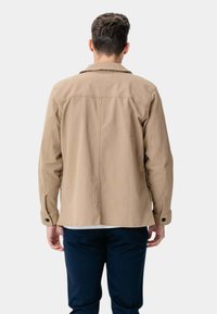 Beige bomuldsjakke med en afslappet pasform, knap-lukninger ved ærmerne og krave. Den har en glat tekstur og et ensartet design, set fra ryggen.