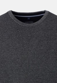 Donkergrijze gebreide trui met een ronde hals. De textuur is ruw en heeft een consistent patroon. Het label zegt "CASA C MODA."
