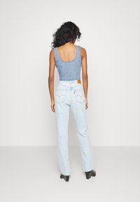 Denimlinne med rundad baksida, tillsammans med högmidjade ljusblå jeans. Texturerad, normal passform, med en läderlapp på midjebandet.