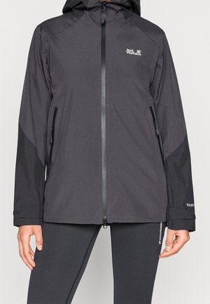 Schwarze Kapuzenjacke von Jack Wolfskin mit Frontreißverschluss und seitlichen Reißverschlusstaschen, getragen von einer Person, sichtbar vom Hals bis zu den Hüften.