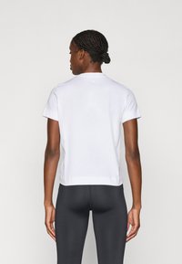 Valge lühikeste varrukatega t-särk ümmarguse kaelusega, valmistatud siledast puuvillakangast. Tagapool on minimalistik disain, millel on väike logo.