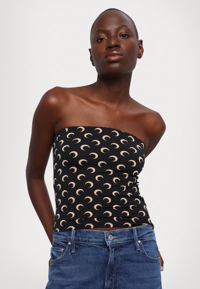 Haut noir sans bretelles avec un motif de croissant de lune crème. Design ajusté, matière extensible, associé à un short en jean bleu.