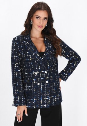 Dunkelblauer, doppelt gestreifter Blazer mit einem strukturierten, gewebten Muster, das blaue, weiße und gelbe Akzente aufweist; große Knöpfe; und geknöpfte Revers.