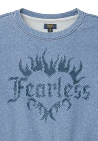Sudadera de mezclilla azul con cuello redondo. Presenta un gráfico oscuro de "Fearless" y un diseño de llamas acentuado con puntos blancos.