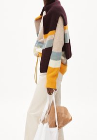 Pull en maille multicolore avec un col haut, présentant des rayures violettes, jaunes, bleues et beiges. Comprend un cordon de serrage et des poignets côtelés.