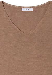 Pull marron en maille avec col en V, coutures visibles et étiquette blanche de marque indiquant "Cecil" à l'intérieur de l'encolure.