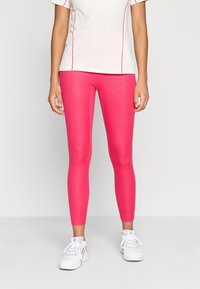Strakke leggings in felroze met een gestructureerd patroon. Gematcht met een witte top met korte mouwen en roze accenten.