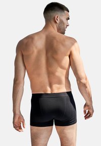 Svarta boxertights tillverkade av mjukt tyg, med en åtsittande passform, bred elastisk midja och minimala söm detaljer.
