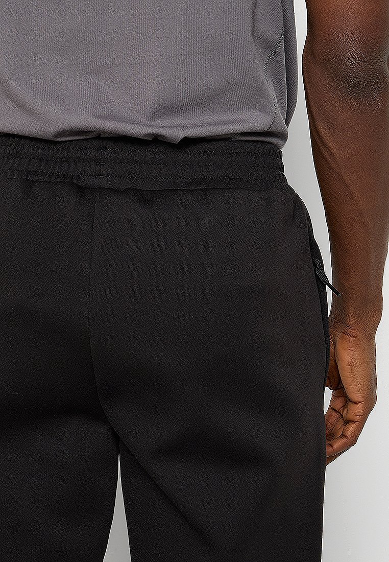 Pantalons noirs avec une taille élastique, dotés d'un cordon de serrage. Texture de tissu lisse, design fuselé et une poche latérale zippée.