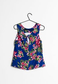 Top senza maniche con motivo floreale, sfondo blu, con accenti rosa e verdi. Scollatura rotonda con dettaglio a lacci sul retro.
