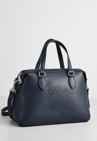 Granatowa skórzana torebka z dwoma górnymi uchwytami, odpinanym paskiem i perforowanym okrągłym logo. Zamykana na suwak, z akcentami w srebrnym kolorze.