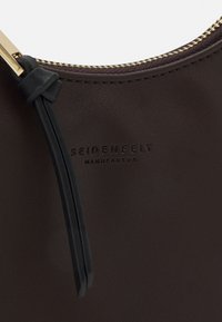 Pochette en cuir marron foncé avec fermeture éclair dorée et tirette en cuir noir, estampillée du logo "SEIDENFELT MANUFAKTUR".