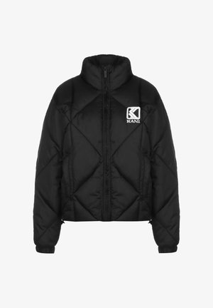 Črni pufast plašč z visokim ovratnikom, prešit vzorec in sprednjim zadrgo. Ima majhno belo oznako na levi strani prsnega koša.