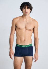 Marineblauwe boxershorts met groene merkband. Gemaakt van zachte stof, met een strakke pasvorm en een eenvoudig stikselontwerp.