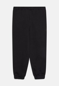 Svarta sweatpants med elastisk midja, avsmalnande anklar och mjukt, texturerat tyg. Inga fickor eller ytterligare detaljer synliga.