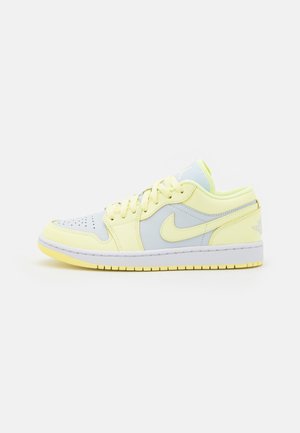 Lavskåret Nike Air Jordan sneaker i bleg gul og lysegrå med snørebånd og hvid sål med gul slidbane.