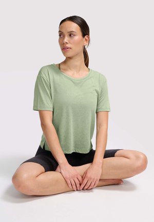 Lichtgroene T-shirt met korte mouwen, gemaakt van zachte stof, met een relaxte pasvorm en ronde halslijn, gecombineerd met donkere shorts.