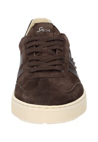 Baskets en daim marron avec une semelle en caoutchouc crème, des accents en tissu sur les côtés, six œillets pour les lacets et un petit logo sur la languette.